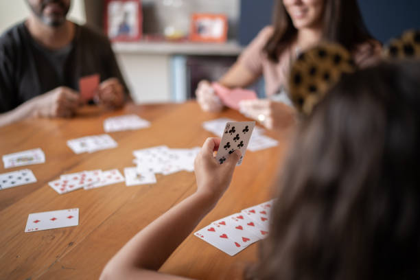 Over the shoulder view of girl holding card Over the shoulder view of girl holding card family playing card game stock pictures, royalty-free photos & images