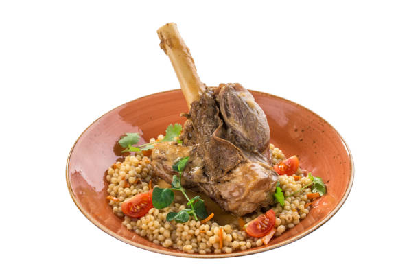Roast lamb shank with peas on orange plate isolated on white background