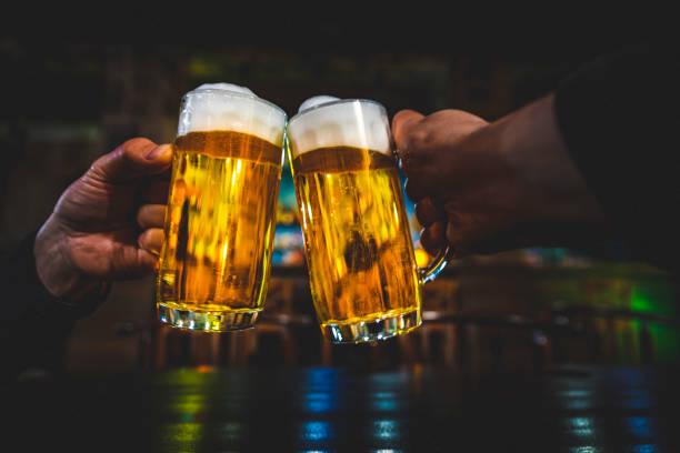 Vue de plan rapproché d’un verre de deux bière à la main. Glaces de bière clinking dans le bar ou le pub - Photo