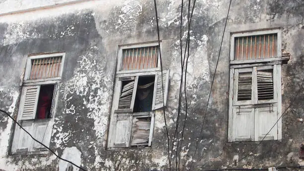Old derelict building in Stone Town, Zanzibar. There is no paint left on the walls and the wooden doors are broken