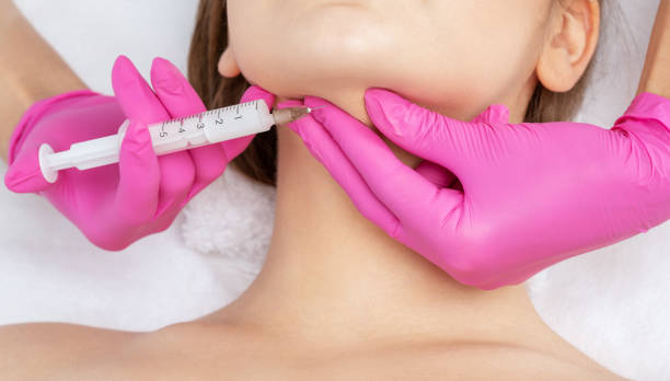 Cosmetologist makes lipolytic injections to burn fat on the chin, cheeks and neck of a woman against double chin. Female aesthetic cosmetology in a beauty salon.Cosmetology concept. Cosmetologist makes lipolytic injections to burn fat on the chin, cheeks and neck of a woman against double chin. Female aesthetic cosmetology in a beauty salon.Cosmetology concept. thin neck stock pictures, royalty-free photos & images