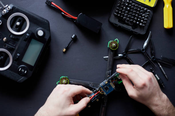 istock Close up of man's hands assembling a FPV drone from parts, using tools, Preparing high-speed racing quadcopter for flight. Repair drone before training process. 1307416878