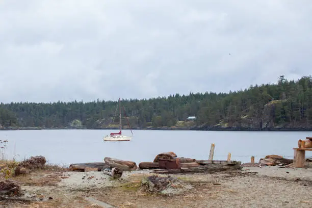 A sailboat sits at anchor in Bucaneer bay, of Thormanby Island on the coast of British-Columbia. A very popular anchorage for boaters and cruisers to explore the sandy beaches of the island