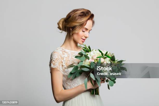 Portrait Of Beautiful Bride Holding Flowers Stock Photo - Download Image Now - Bride, Fashion Model, Gray Background