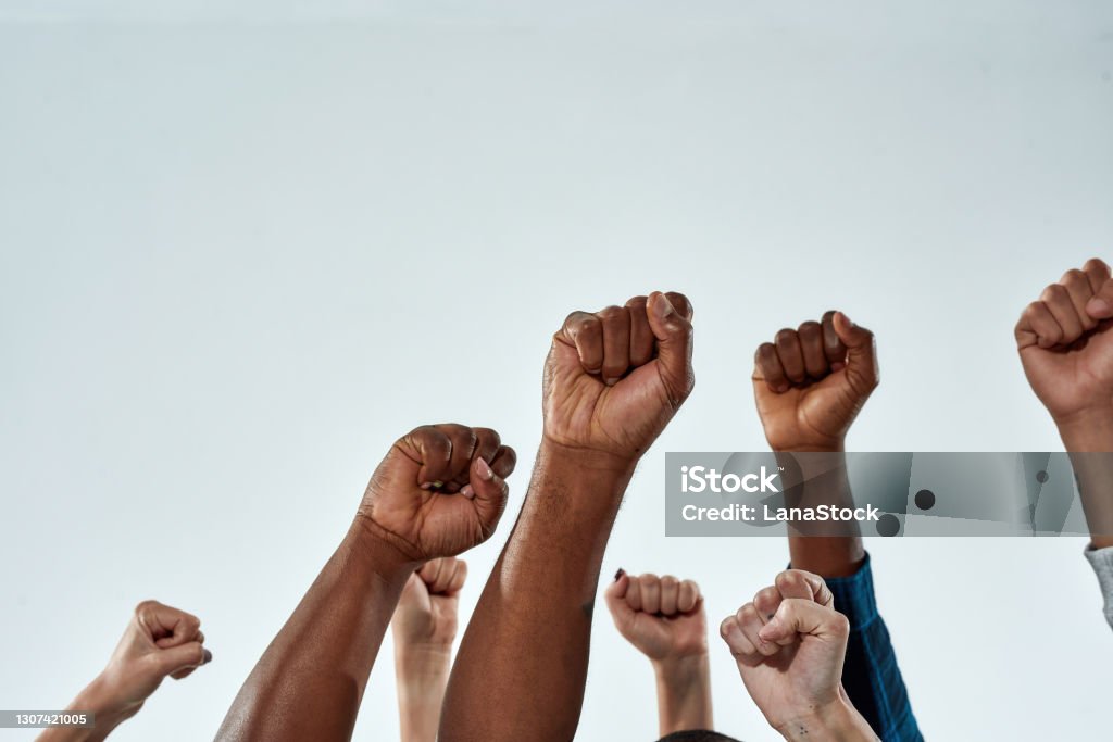 Raised hands of multiracial people clenched into fists Raised hands of multiracial people clenched into fists on light background. Stop racism concept Anti-racism Stock Photo