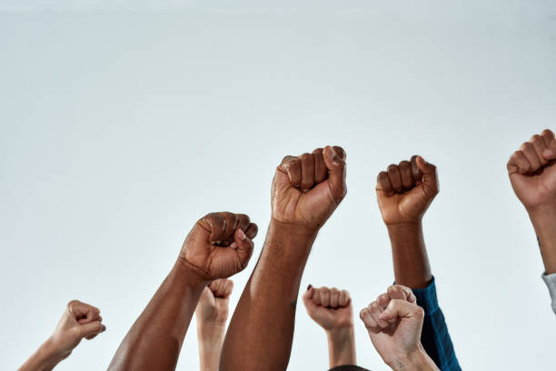 Raised hands of multiracial people clenched into fists stock photo
