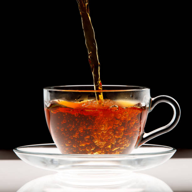 istock Pouring black tea into transparent cup isolated 1307421138
