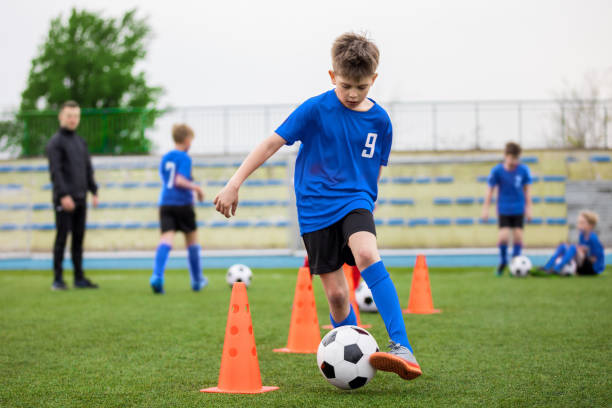 istock Boys attending soccer training on school field. Young man coaching children on physical education class. Soccer practice for children 1307424606