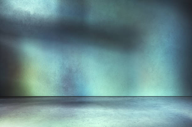 istock Turquoise textured wall and concrete floor in empty room for displaying your product, industrial atmosphere, cross shadow on wall. 1307425695