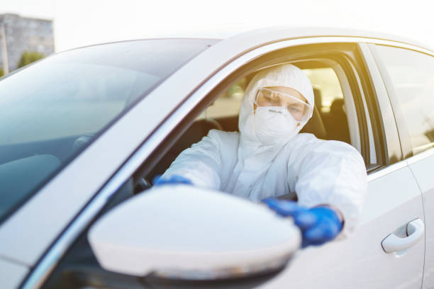 istock Man in virus protective suit and mask driving car. 1307427747