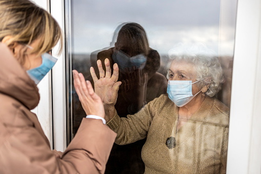 Mujer visitando a su abuela aislada durante una pandemia de coronavirus photo