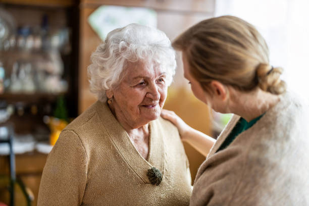 gesundheitsbesucher im gespräch mit einer seniorin während hausbesuch - häusliche pflege stock-fotos und bilder
