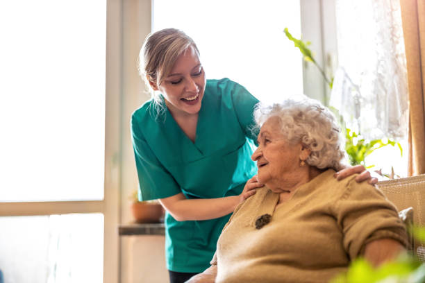 female nurse taking care of a senior woman at home - female nurse imagens e fotografias de stock