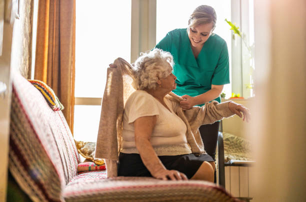 krankenschwester kümmert sich um eine seniorin zu hause - altersheim stock-fotos und bilder