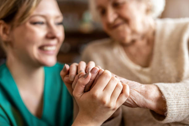 colpo ritagliato di una donna anziana che si tiene per mano con un'infermiera - assisted living foto e immagini stock