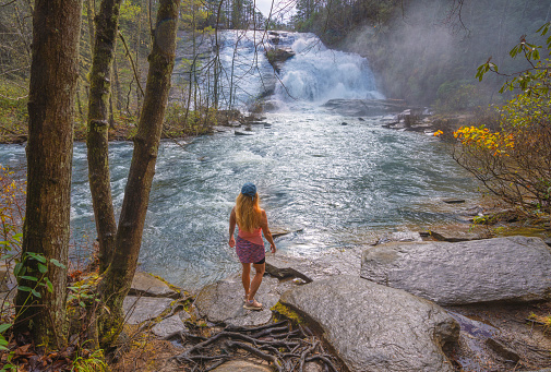 Girl enjoying High Falls  of Dupont State Forest in Brevard. Blue Ridge Mountains, near Asheville, Western North Carolina, USA.