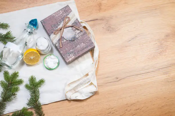 Photo of Save our planet. Eco detergents, fresh fir branches and eco textil bag on wooden table background with blank space for ad. Perfect gift box for trendy, modern responsable family