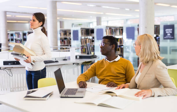 istock Teacher and adult students talking in the library 1307438013