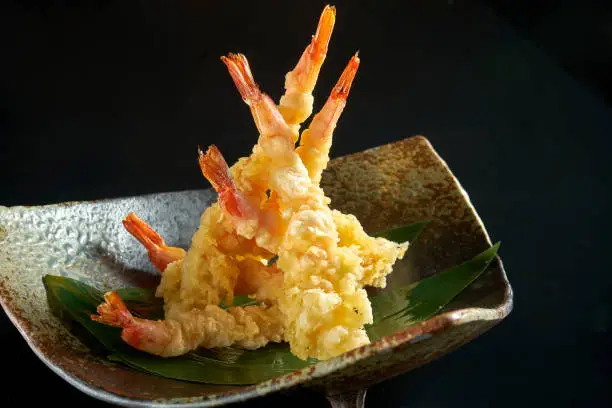 Fried prawn. Shrimp fries in tempura, served in a black Japanese-style bowl. Isolated on a black background. Restaurant food - seafood