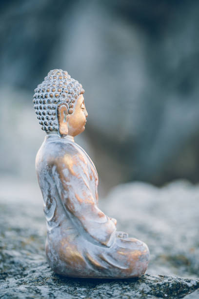 istock Peaceful gold Buddha figure sitting sideways on a rock surrounded by mountains 1307439610