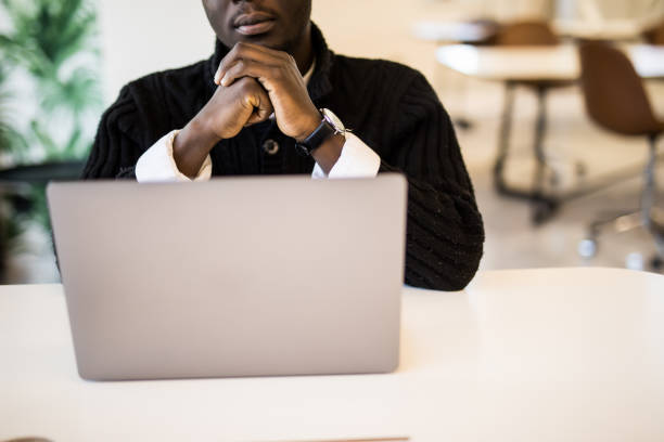 istock Smiling African man working while sitting in office, Concept of young people using mobile devices. 1307443110
