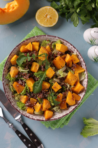 istock Salad with quinoa, pumpkin and arugula in a plate on light blue background. Top view 1307443450