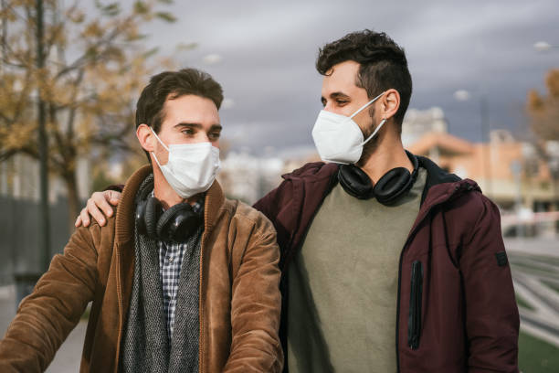 istock Couple of boys with face masks looking lovingly at each other while hugging. 1307451297