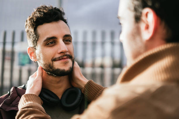 Gay hipster man caresses his boyfriend's face while looking lovingly at him. stock photo
