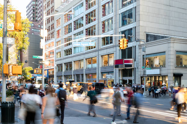 Crowds of people walking across the busy intersection on 14th Street at Union Square Park in New York City NYC Crowds of people walking across the busy intersection on 14th Street at Union Square Park in New York City NYC past the cars and buildings union square new york city stock pictures, royalty-free photos & images