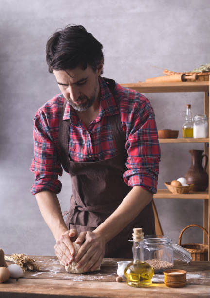 istock Baker man kneading or making dough and bakery ingredients for homemade bread cooking on shelf 1307455133