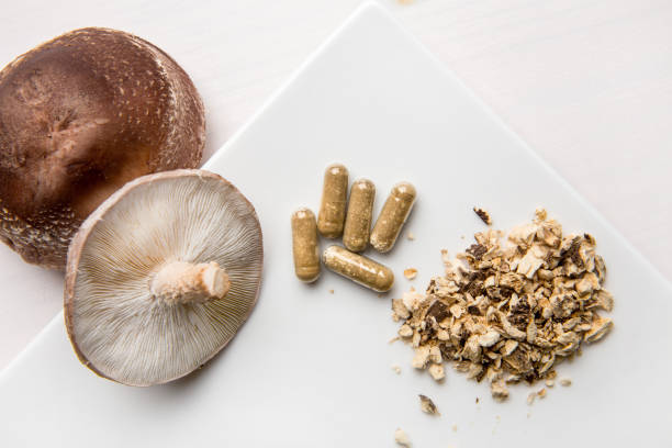 istock Shiitake Lentinus edoides mushroom supplement capsules with fresh Shiitake mushrooms and powdered on white minimal background. Flat lay view. 1307455136