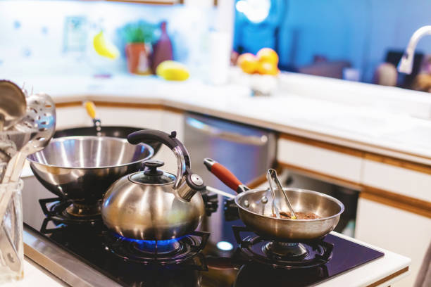 Saucepan sitting on gas stove top with olive oil, clean dishes, and spice rack in a home kitchen setting