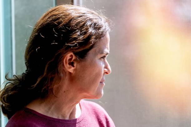 istock Concerned, pensive, unemployed mature woman looking through a window 1307456524