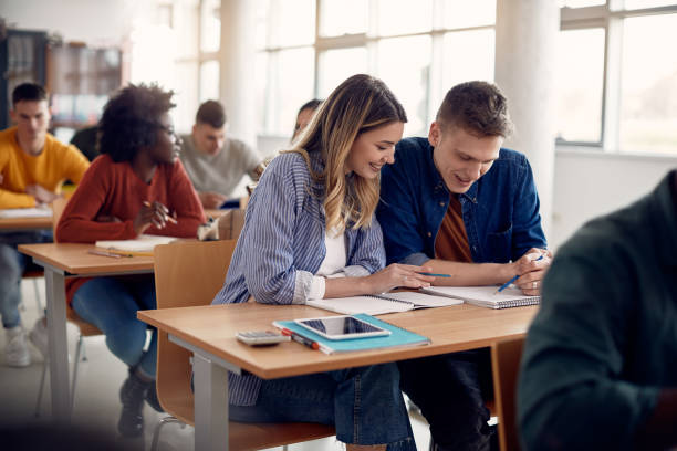 istock Happy university students reading lecture from notebook in lecture hall. 1307456666
