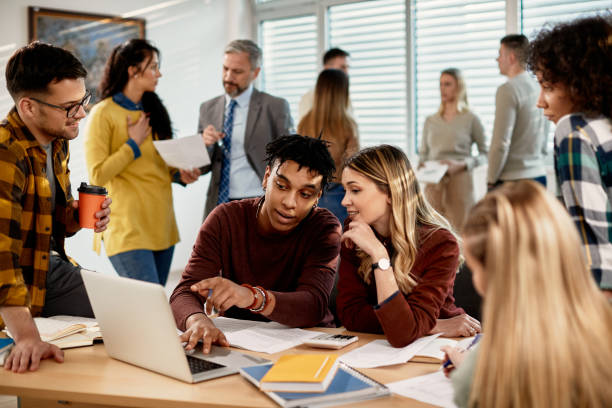 istock College students cooperating while suing laptop in the classroom. 1307456678