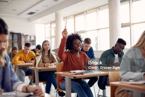 Happy Black Student Raising Arm To Answer Question While Attending Class With Her University Colleagues Stock Photo - Download Image Now