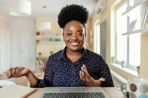 Happy Young African American Woman Blogger Applicant Teacher Sit at Home Office Look at Camera Doing Online Job Interview During Video Chat Conference Call Record Vlog Teaching on Webinar in App, Webcam View