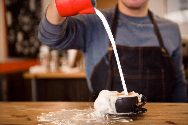 Close up barista pouring too much milk in coffee cup, making latte art