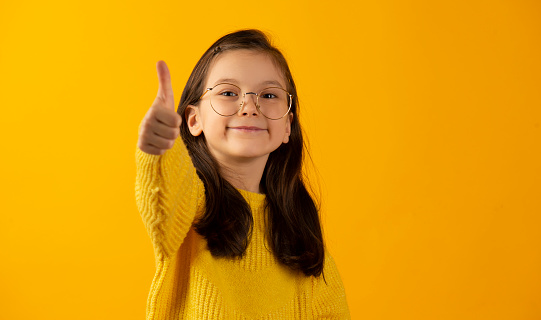 Thumbs up, happy and child in agreement excited, winning and girl kid isolated in studio green screen background. Yes, approval and portrait of young person with yes hands, gesture or sign