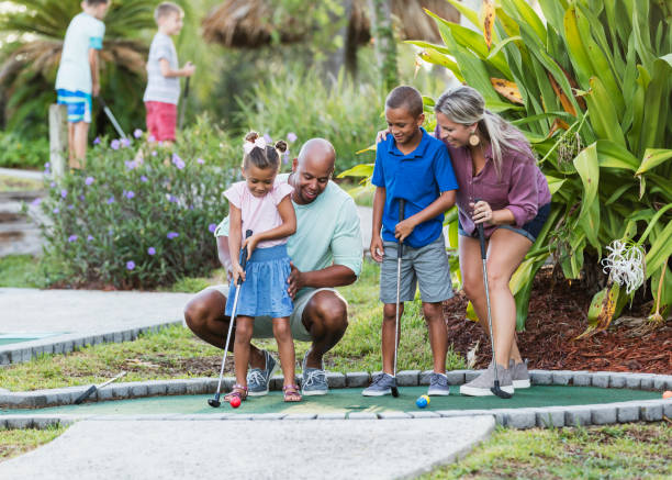 Interracial family, two children playing miniature golf