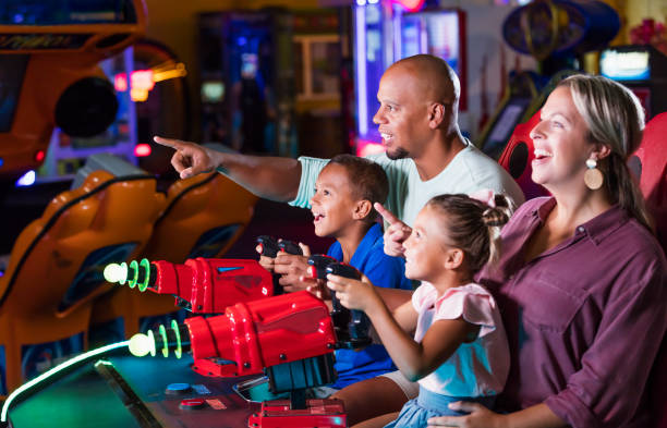 famille mixte de course jouant le jeu à l’arcade vidéo - amusement arcade arcade video game sport photos et images de collection