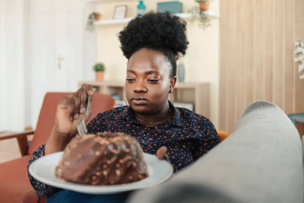 I can't get enough Unhealthy Lifestyle Concept: Overweight African American Woman Eating Junk Food in the Living Room big plate of food stock pictures, royalty-free photos & images