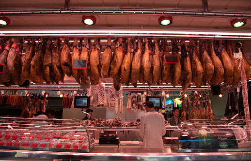 Barcelona, Spain, January 26 2019: Butcher at a meat farmer market counter. Various meat slices at a grocery store. La Boqueria, Barcelona Spain