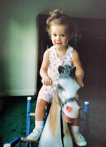 Cute toddler girl in romper riding a h