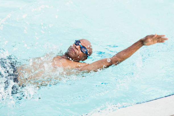 homme afro-américain aîné dans le dos de natation de piscine - dos crawlé photos et images de collection