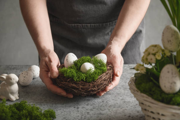 istock Easter table centerpiece with festive eggs, moss and bunny. Spring floral workshop. 1307460079