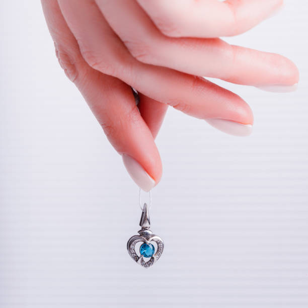 Female hand holding gold necklace jewelry pendant on red background