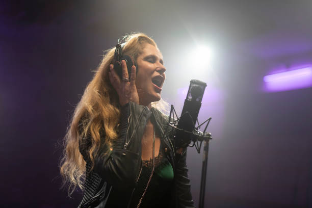 Female singer with eyes closed singing and recording songs in recording studio.