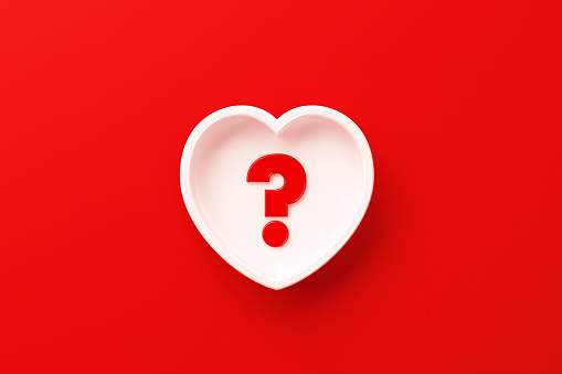 White heart shape with red question mark sitting on red background.  Horizontal composition with copy space. Q and A concept.