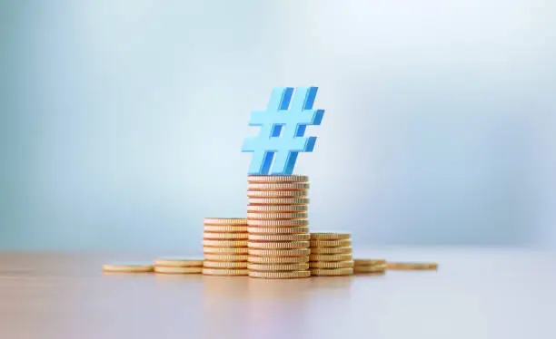 Photo of Blue Hashtag Symbol Sitting On Coin Stacks Before Defocused Background